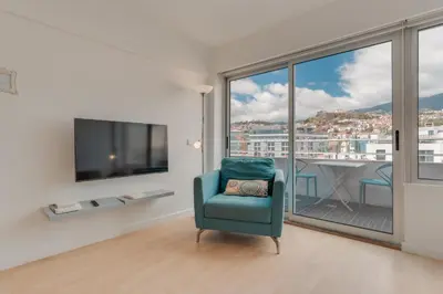 a living room with a blue chair and a large window at Arriaga apartment in Funchal