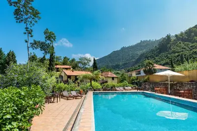 a swimming pool with tables and chairs and a mountain at Pestana Quinta do Arco Nature & Rose Garden Hotel in Arco de São Jorge