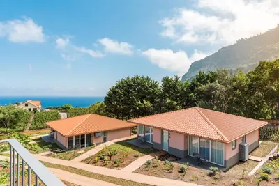 a view of two houses with the ocean in the background at Pestana Quinta do Arco Nature & Rose Garden Hotel in Arco de São Jorge