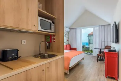 a hotel room with a bed and a kitchen with a sink at Pestana Quinta do Arco Nature & Rose Garden Hotel in Arco de São Jorge