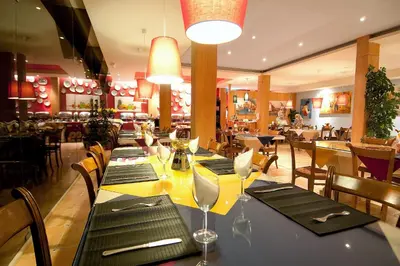a restaurant with a long table with black napkins and wine glasses at Luzmar Villas in Luz