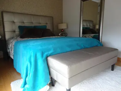 a bedroom with a bed with a blue blanket and a mirror at Apartamento Raio de Sol in Caniço
