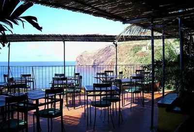 a group of tables and chairs on a patio overlooking the ocean at Apartamento Raio de Sol in Caniço