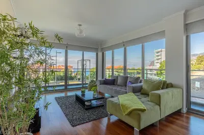 a living room with a couch and large windows at Monumental Residence apartment with pool by HR Madeira in Funchal