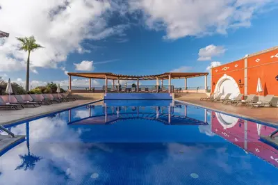 a swimming pool with chairs and a gazebo at Palheiro Village Resort in Funchal