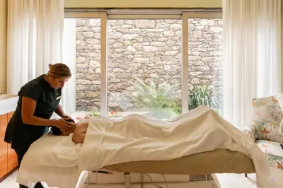 a woman preparing a person on a bed at Palheiro Village Resort in Funchal