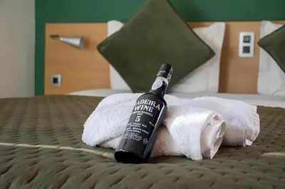 a bottle of wine sitting on top of towels on a bed at Casa Os Manos in Santana