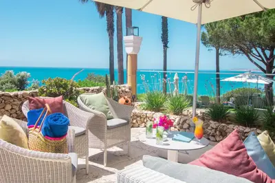 a patio with chairs and an umbrella and the ocean at Boutique Hotel Vivenda Miranda in Lagos