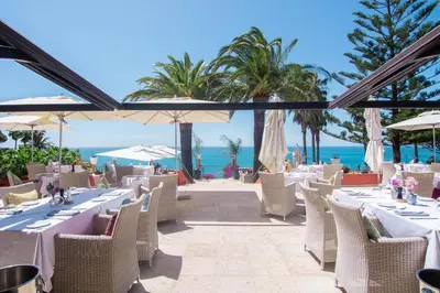 a restaurant with white tables and chairs and the beach at Boutique Hotel Vivenda Miranda in Lagos