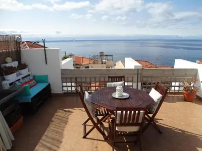 a table and chairs on a balcony with a view of the ocean at Barreirinha Funcho House in Funchal