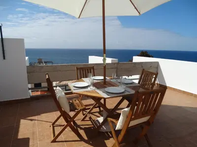 a wooden table with chairs and an umbrella on a balcony at Barreirinha Funcho House in Funchal