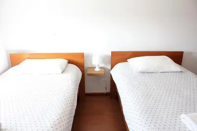 two beds in a room with white sheets at Lilas' Private Accommodation in Vila do Bispo