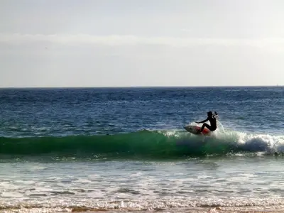 a person riding a wave on a surfboard in the ocean at Lilas' Private Accommodation in Vila do Bispo