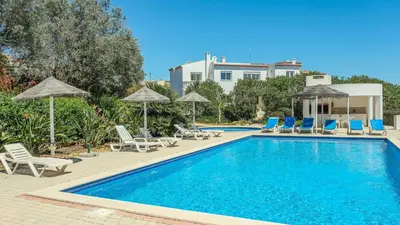 a swimming pool with chairs and umbrellas at Casas do Ramalhete in Luz