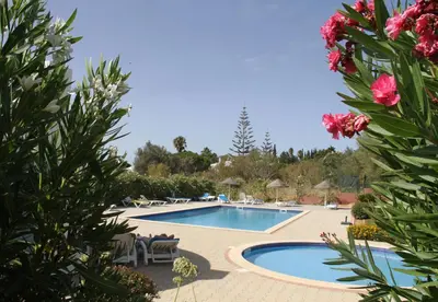 a swimming pool with tables and chairs and flowers at Casas do Ramalhete in Luz