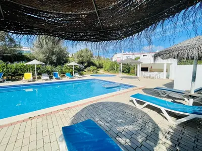a swimming pool with two chairs and an umbrella at Casas do Ramalhete in Luz