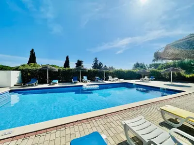 a large swimming pool with chairs and umbrellas at Casas do Ramalhete in Luz