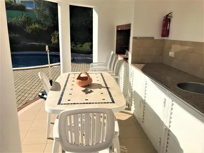 a kitchen with a table and chairs on a balcony at Casas do Ramalhete in Luz