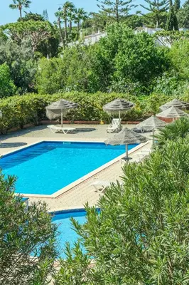 a large swimming pool with umbrellas and chairs at Casas do Ramalhete in Luz