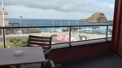 a view of the ocean from a balcony with a table at Hotel Salgueiro in Porto Moniz
