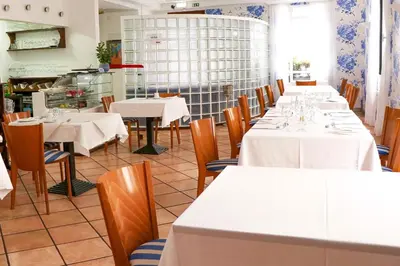 a dining room with tables and chairs with white tablecloths at Amparo in Machico