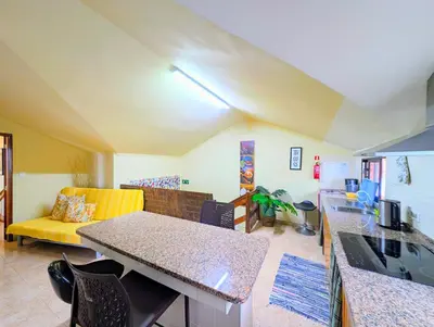 a living room with a yellow couch and a kitchen at Paul do Mar BY SEA in Paul do Mar
