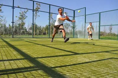 a man hitting a tennis ball on a tennis court at Martinhal Sagres Beach Family Resort Hotel in Sagres