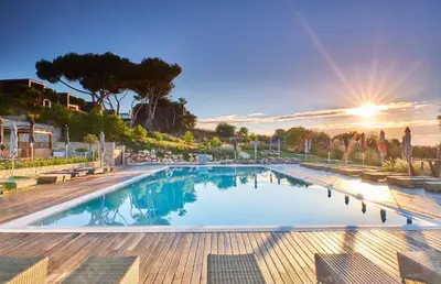 a large swimming pool with the sun in the background at Martinhal Sagres Beach Family Resort Hotel in Sagres