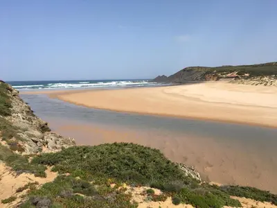a sandy beach with the ocean in the background at Casa Trinta - Praia da Arrifana in Praia da Arrifana
