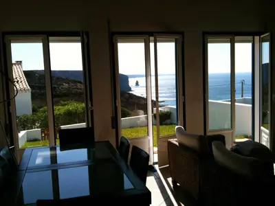 a living room with a table and a view of the ocean at Casa Trinta - Praia da Arrifana in Praia da Arrifana