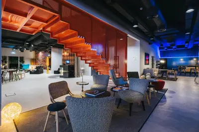 a lobby with a staircase with chairs and tables at Pestana CR7 Funchal in Funchal