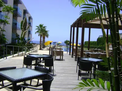 a restaurant with tables and chairs and the ocean at Golden Residence Hotel in Funchal