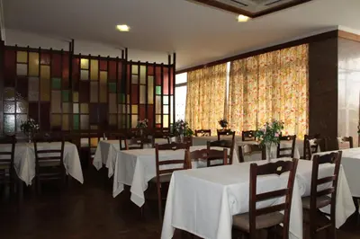 a dining room with white tables and chairs and stained glass windows at Residencial Greco in Funchal