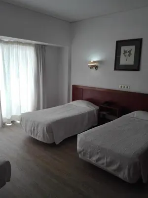 a hotel room with two beds and a window at Residencial Greco in Funchal
