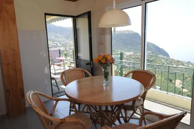a table with chairs and a vase of flowers on a balcony at Casa Daniela in Calheta