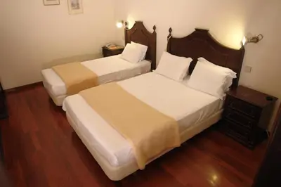 two beds in a hotel room with wooden floors at Hotel Sirius in Funchal