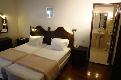 a hotel room with two beds and a bathroom at Hotel Sirius in Funchal
