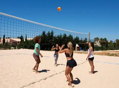 a group of women playing volleyball on the beach at Aldeia Azul Resort in Lagos