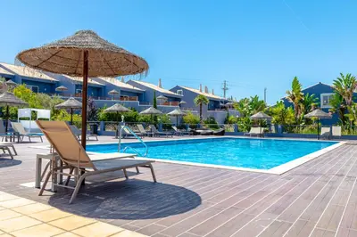 a pool at a resort with a chair and an umbrella at Aldeia Azul Resort in Lagos