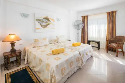 a bedroom with two beds and a table and a lamp at Maio Apartment in Luz