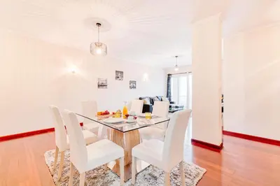 a dining room with a glass table and white chairs at Vip VI - Sea view apartment in Caniço