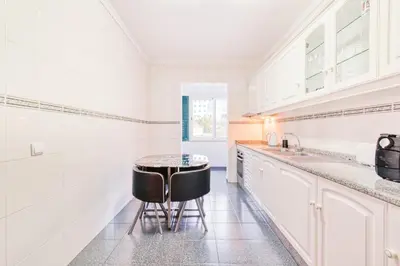 a white kitchen with a table and two stools at Vip VI - Sea view apartment in Caniço