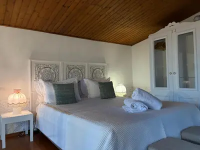 a bedroom with a white bed with a wooden ceiling at Casa do Poço Funchal in Funchal