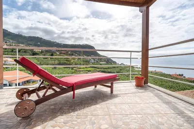 a red chair sitting on a balcony with a view at Apartment Annie 2 in Arco da Calheta