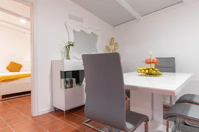 a white dining room with a table and a chair at Apartment Annie 2 in Arco da Calheta