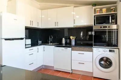 a kitchen with white cabinets and a washer and dryer at Apartment Annie 2 in Arco da Calheta