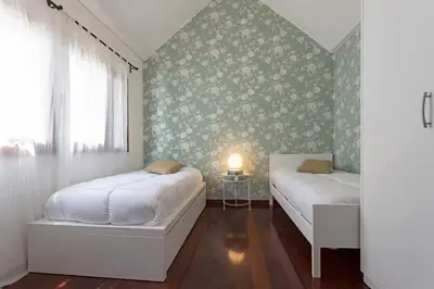 two beds in a bedroom with floral wallpaper at Casa do Lugar de Baixo in Ponta do Sol