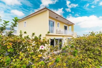 a yellow house with a balcony on top of some bushes at Villa dos Anjos in Porto Santo