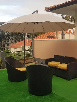 a patio with two chairs and an umbrella at FX Pena in Funchal