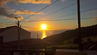 a sunset with the sun setting over the ocean at Hostel Casal São João in Ribeira Brava